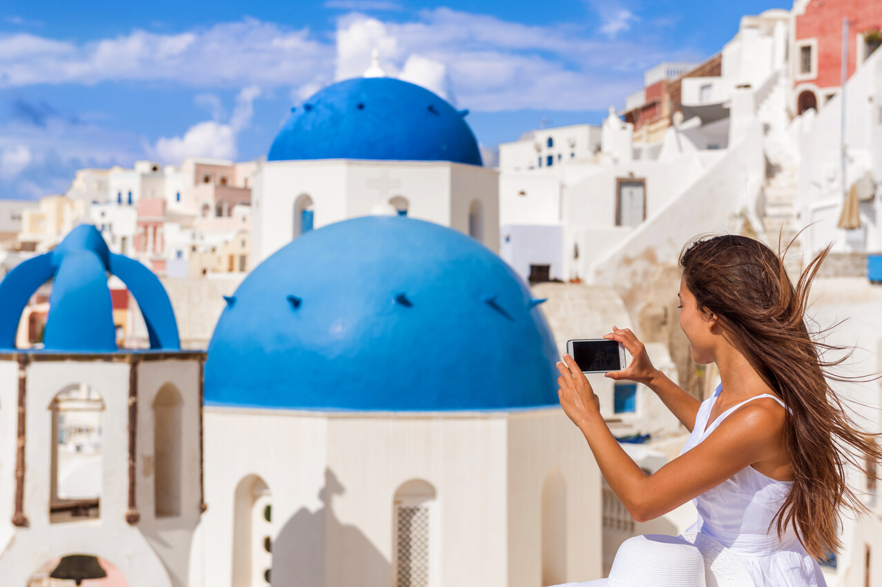 Travel Woman Taking Phone Picture of Santorini